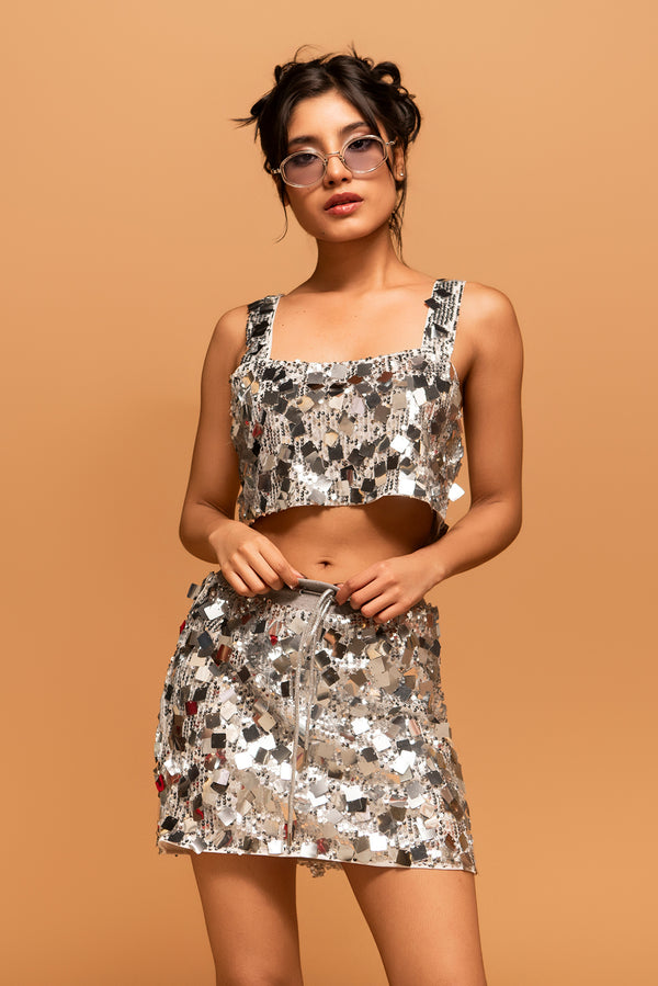 Mujer modelando top y falda plateada